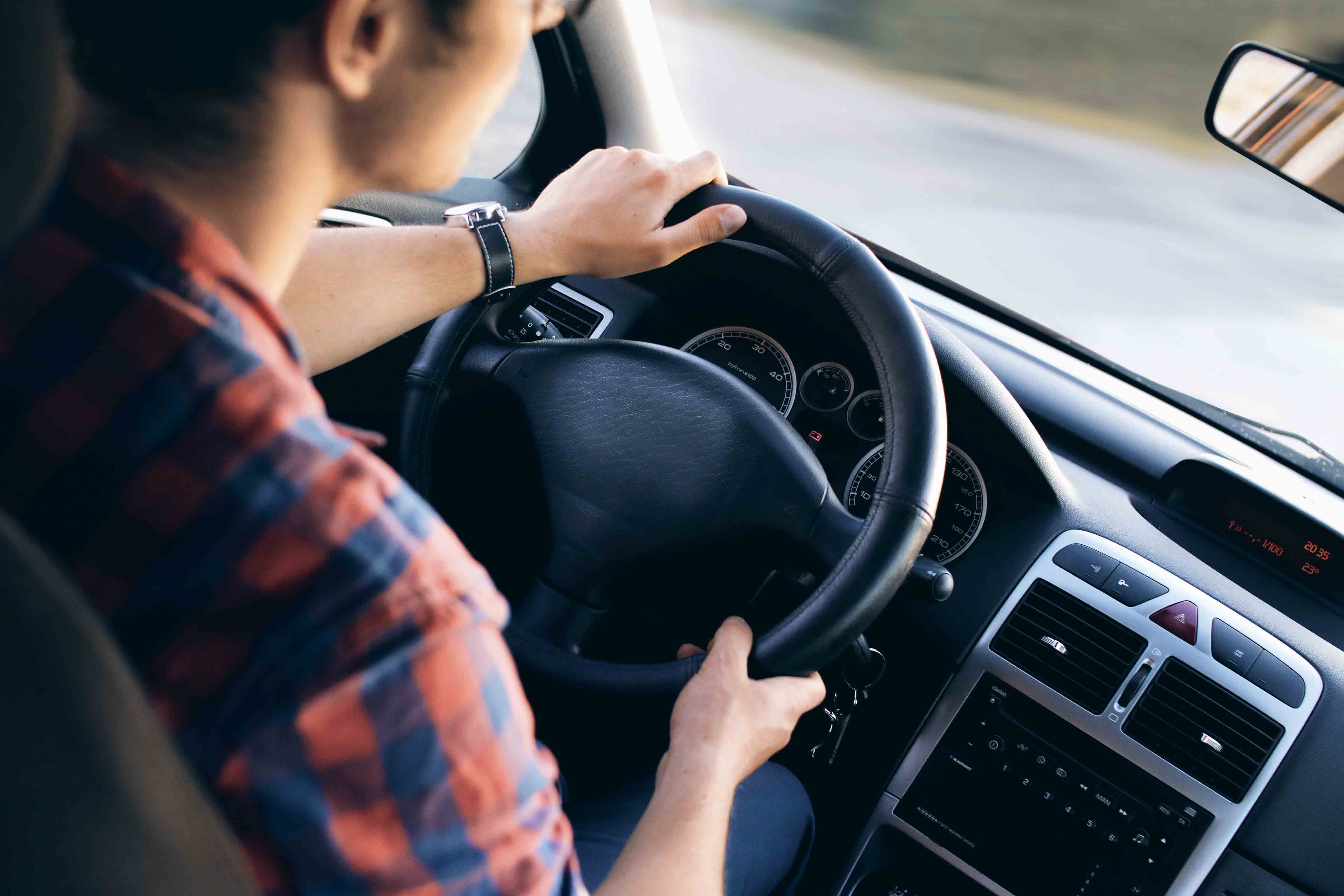 Young driver in his shirt in a nice modern car in motion