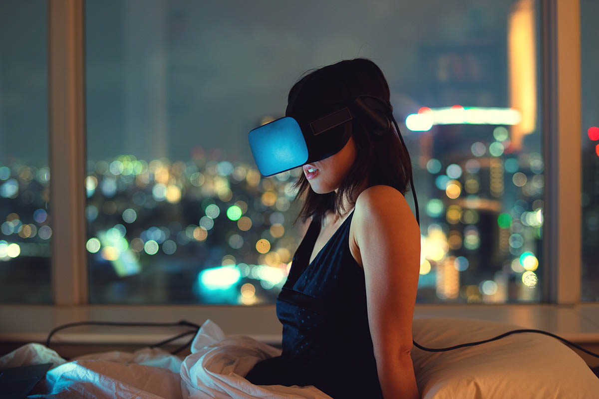 Woman using virtual reality headset at night with city lights in background