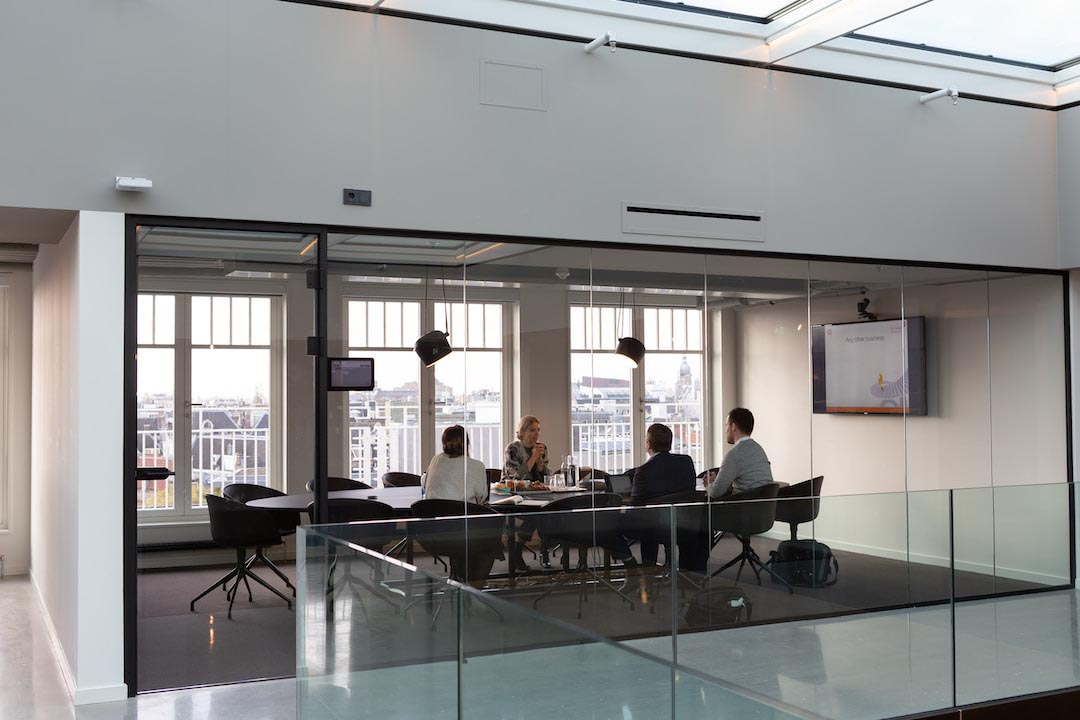 Four people sitting in a conference room with glass windows discussing resource utilization.